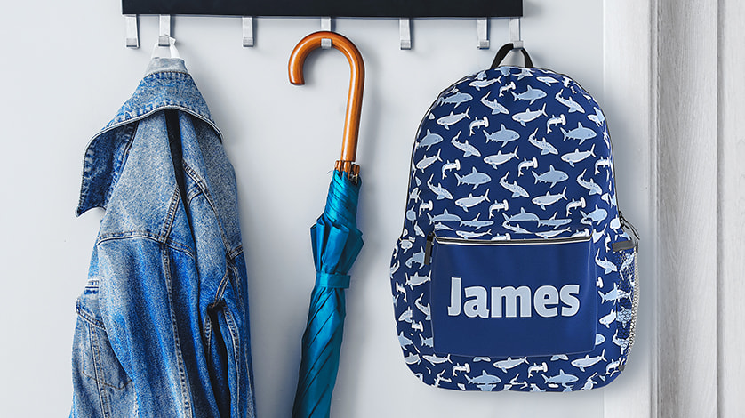 Personalized Backpacks: A children's backpack with a shark pattern, personalized with the name James.