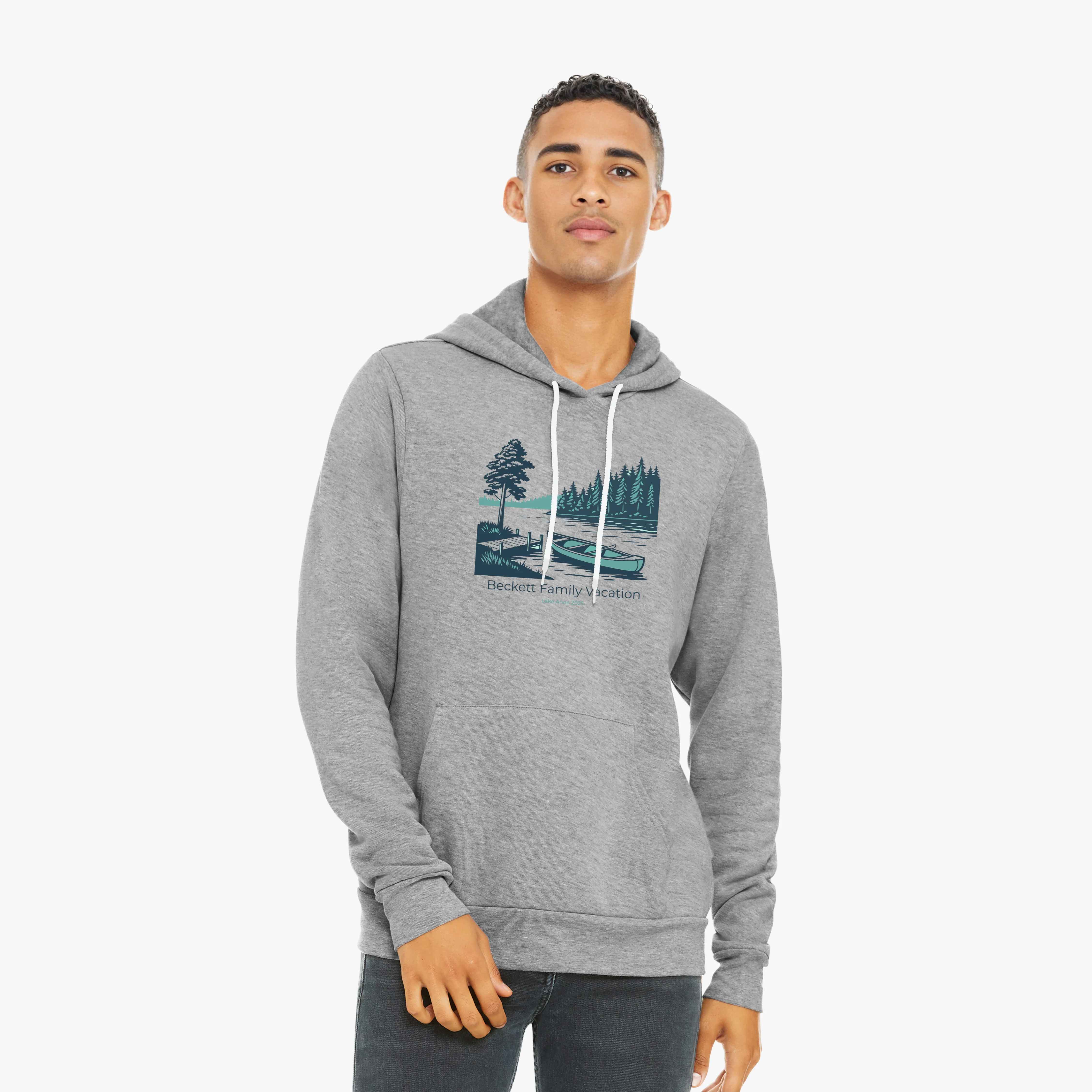 Unisex Sponge Fleece Hoodie Athletic Heather, Size S: A model wearing a heather gray hoodie with a custom family vacation graphic of a lake scene.