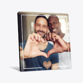 Square desk art print of a couple making a heart shape with their hands in a white frame.