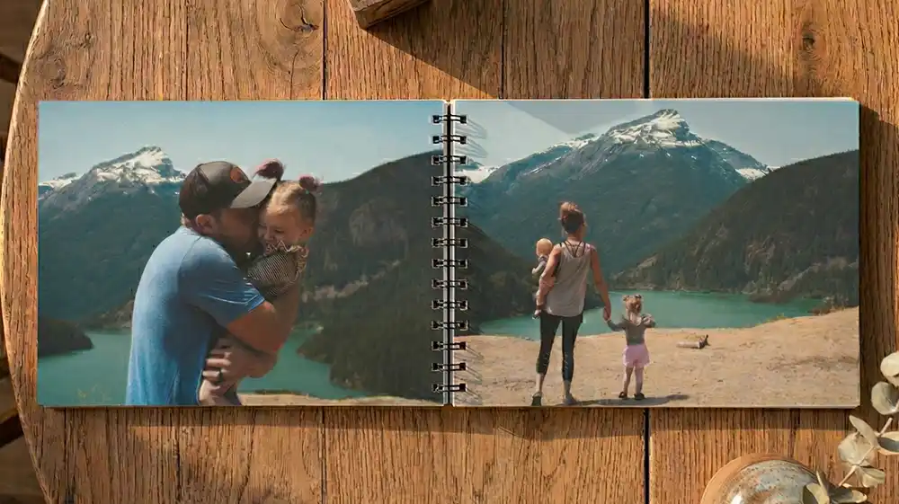 Custom photo books showing an open spiral flip book featuring family landscape photos on a rustic wood surface.