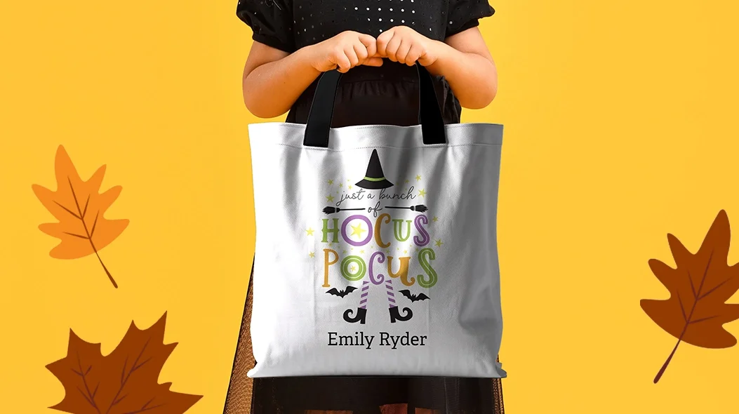 Tricks And Treats: A child holding a white Halloween trick-or-treat tote bag with the text just a bunch of HOCUS POCUS, featuring a witch's hat, legs, and a personalized name.